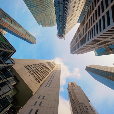 Looking up high-rise buildings, skyscrapers, architectures in smart city for technology background in Singapore City with blue sky